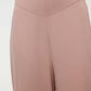 A woman wears pink pajama pants and shows her waistband