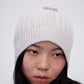 Woman wearing cream wool beanie and facing right