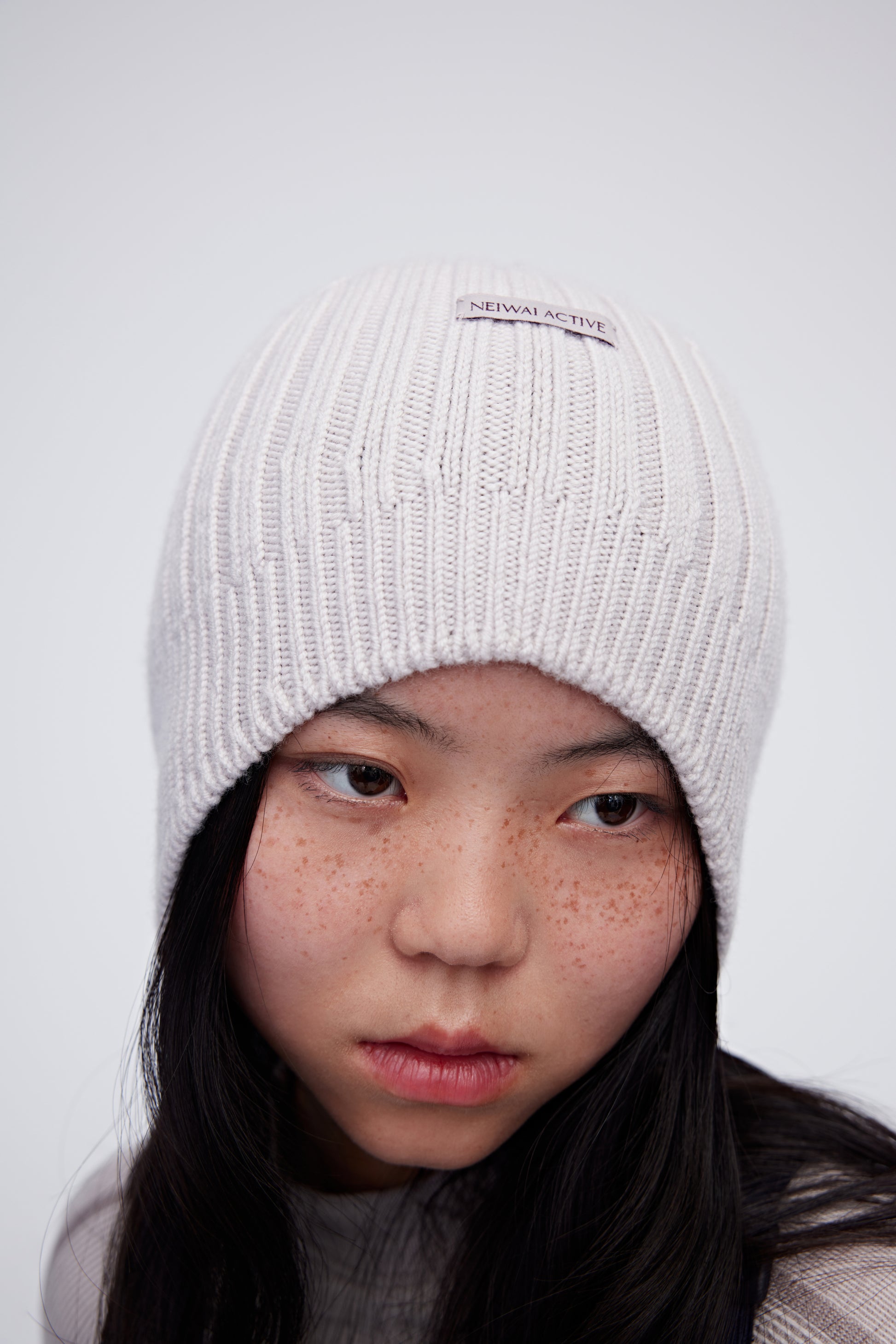 Woman wearing cream wool beanie and facing right