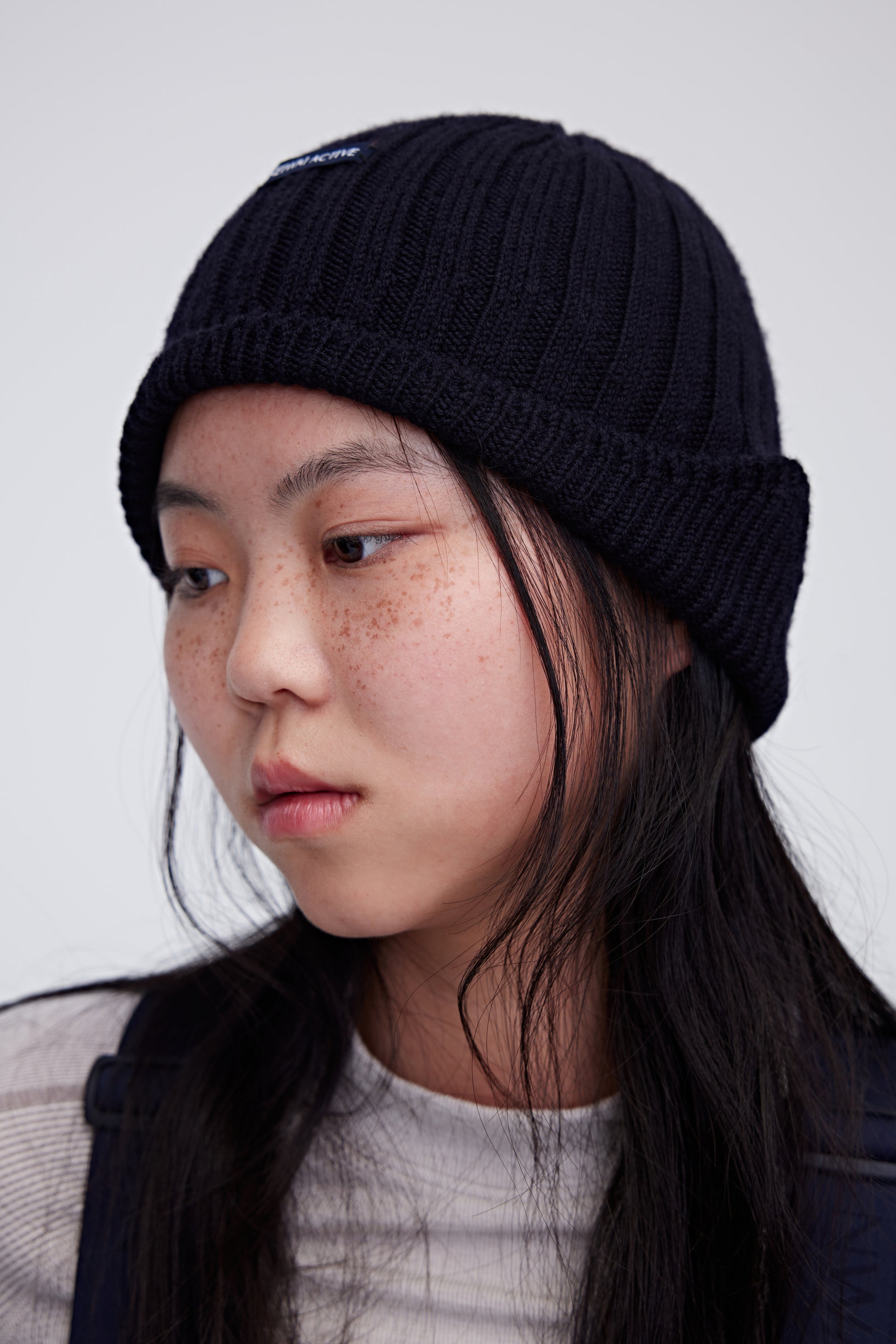Woman wearing navy wool beanie and facing left
