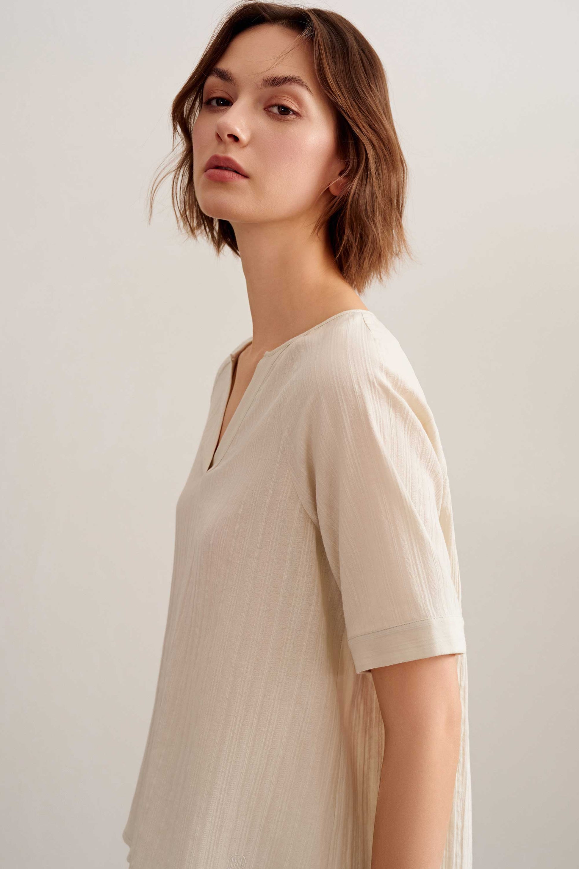 a woman wearing a light beige v neckline short sleeve tee.