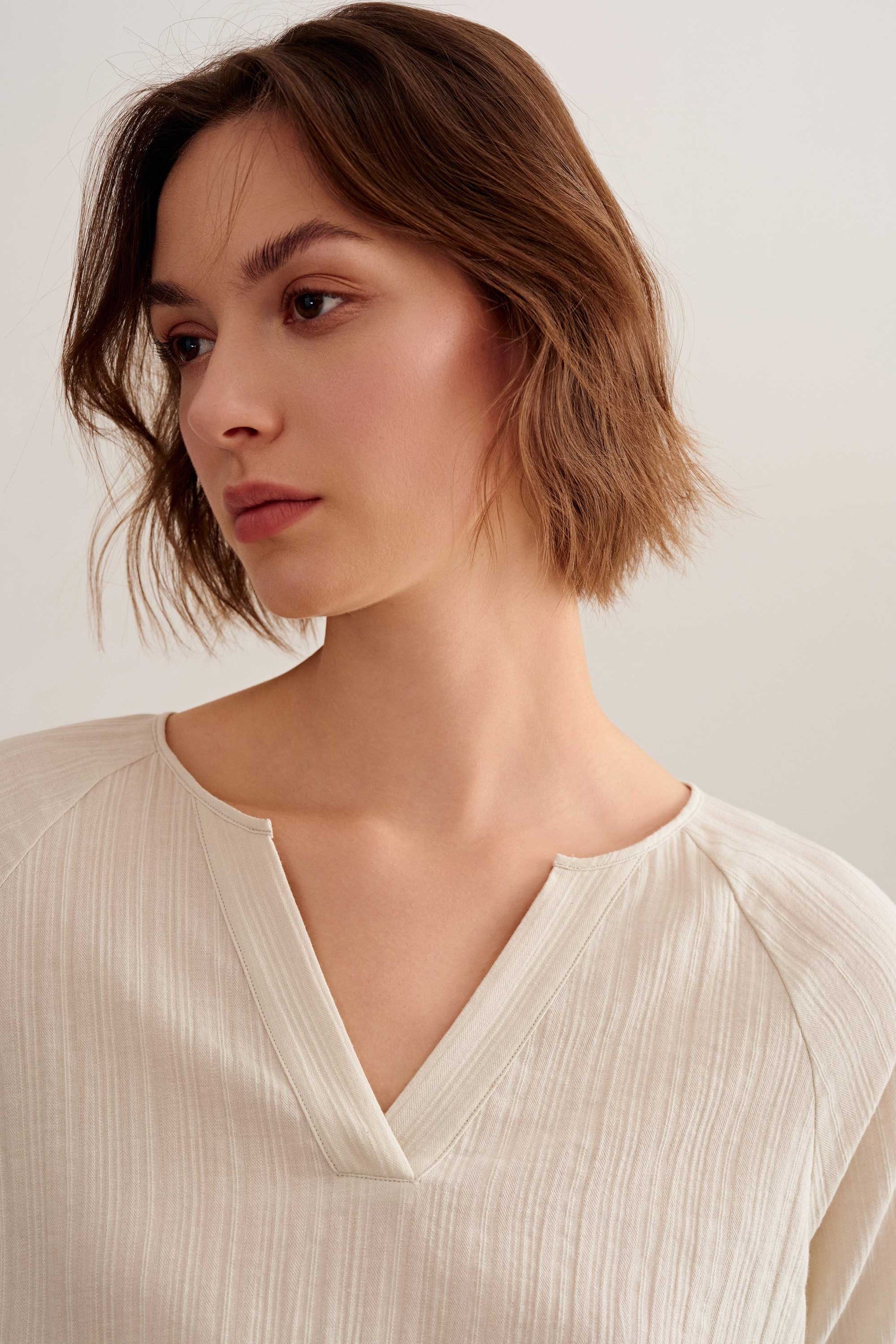 a woman wearing a light beige v neckline short sleeve tee.