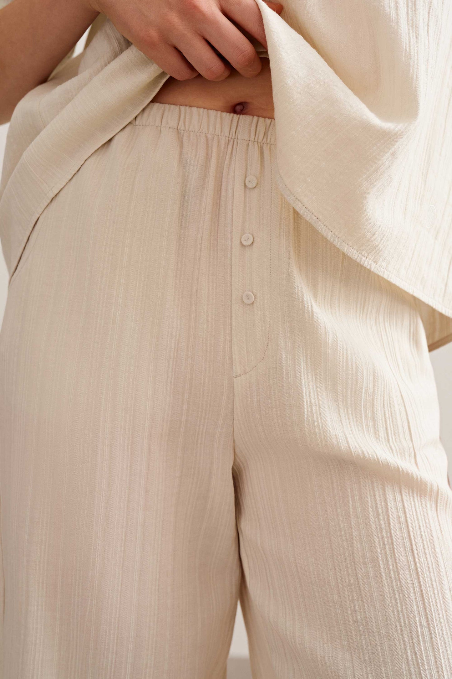 a woman wearing a light beige pants with three button. 