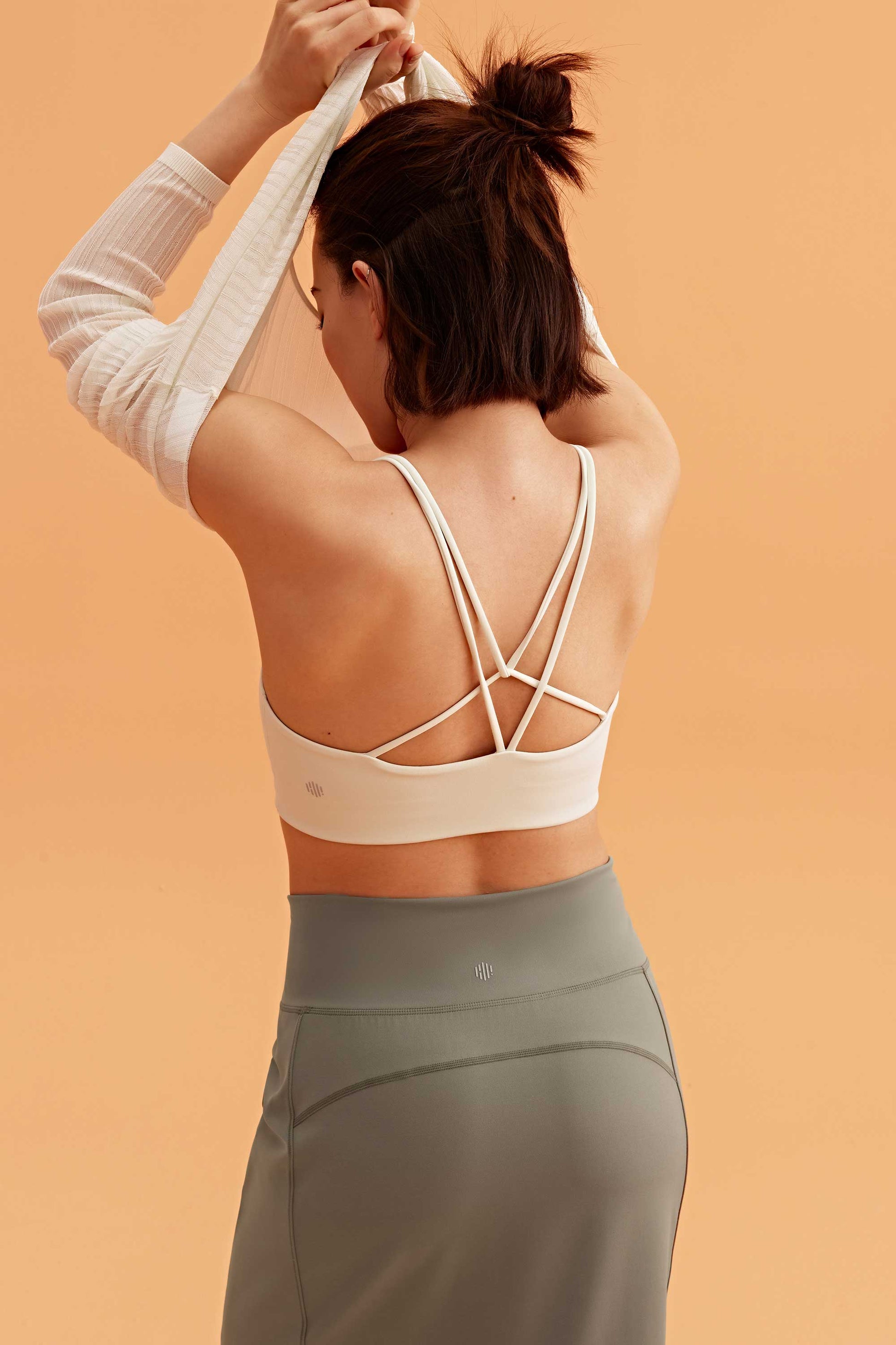 back of a woman wearing a white sports bra and grey skirt. 