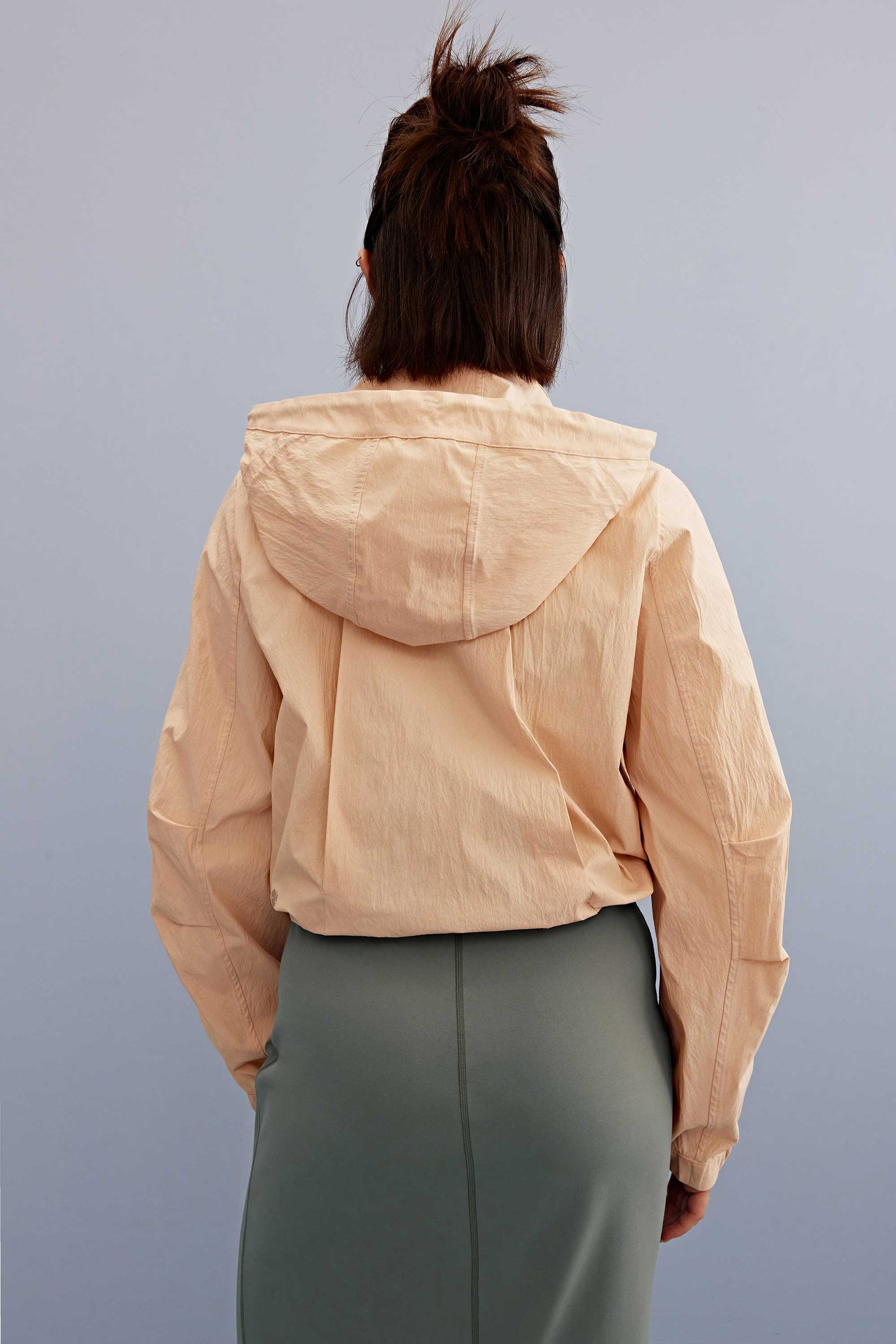 back of a woman wearing a warm yellow jacket and green skirt