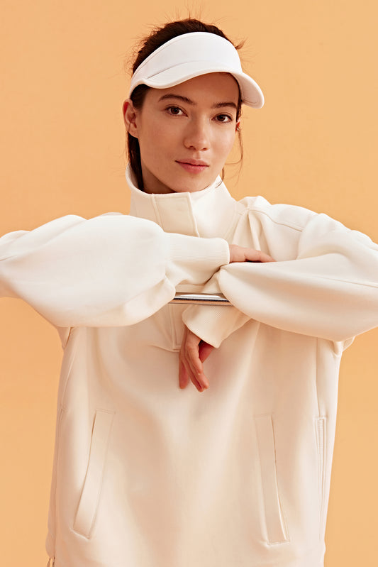 woman wearing a white visor and white half zip sweatshirt