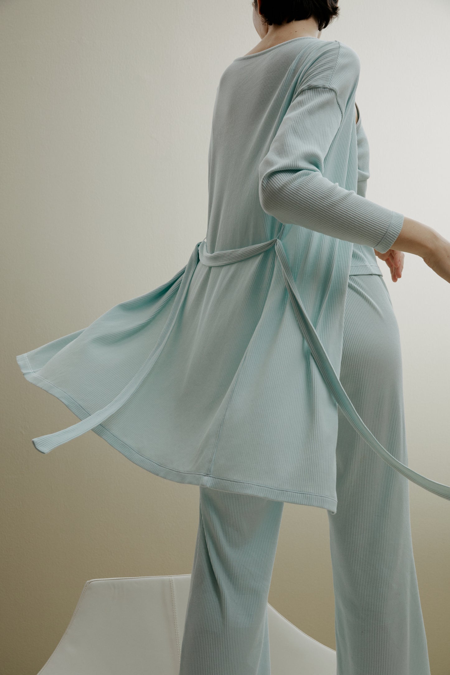 back of women in pale blue ribbed cardigan and pants