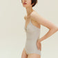 Side view of woman wearing gold one piece swimsuit with spaghetti straps and keyhole neckline design