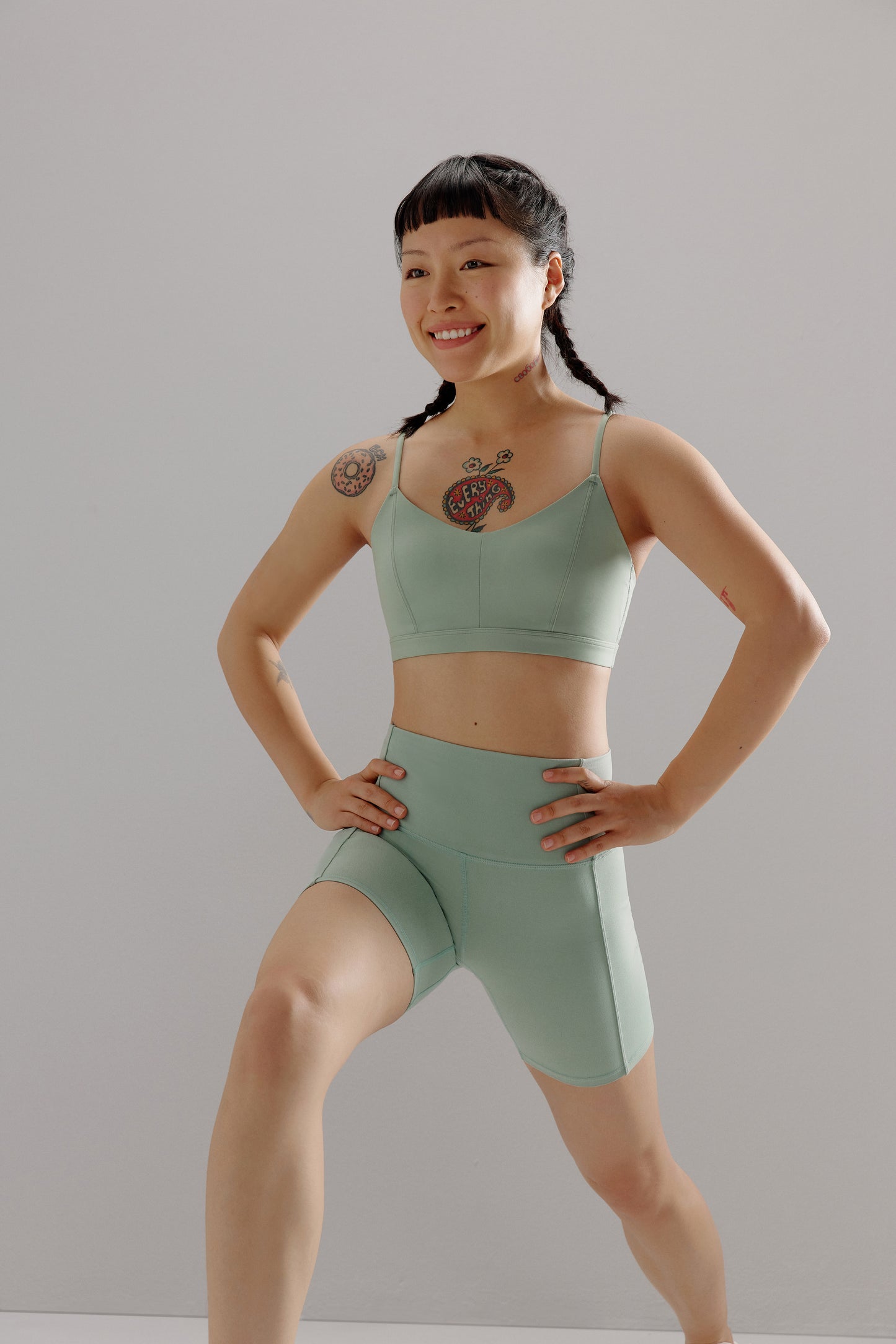 A woman wears a teal sports bra and shorts.