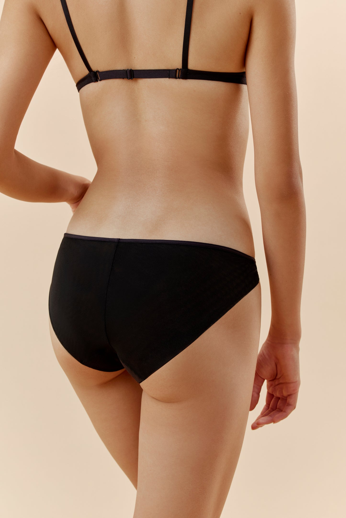 back of a woman wearing a black brief and black bra 