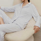 a woman wearing a light blue pajama set sitting on a white sofa