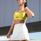 woman in yellow sports bra and white tennis skort