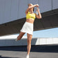 woman in yellow sports bra and white tennis skort