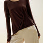 A woman wears a brown sweater and beige pants