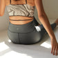 back of a woman wearing a marble print sports bra, dark grey leggings.