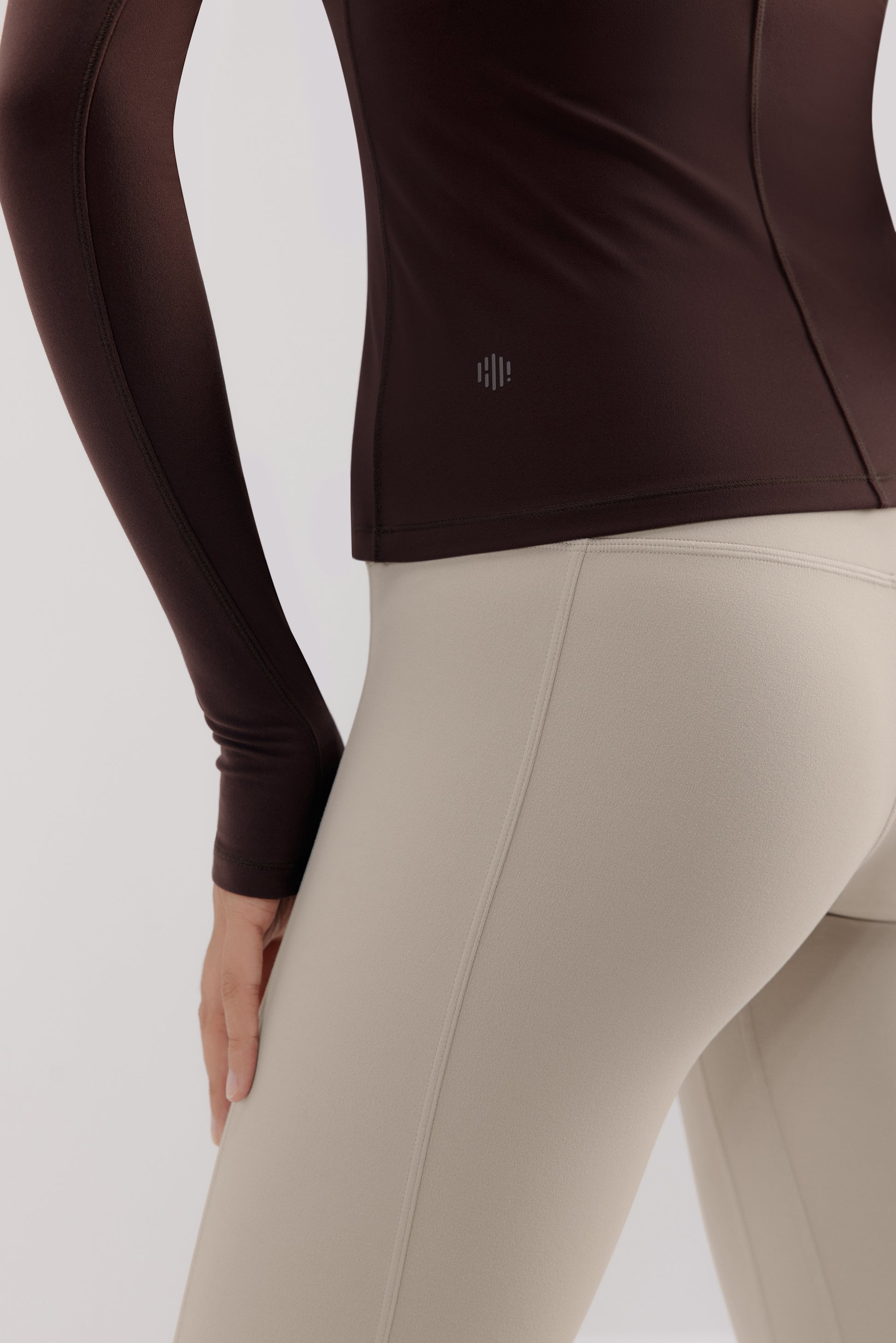close up of a brown mousse long sleeve sports top and grey leggings