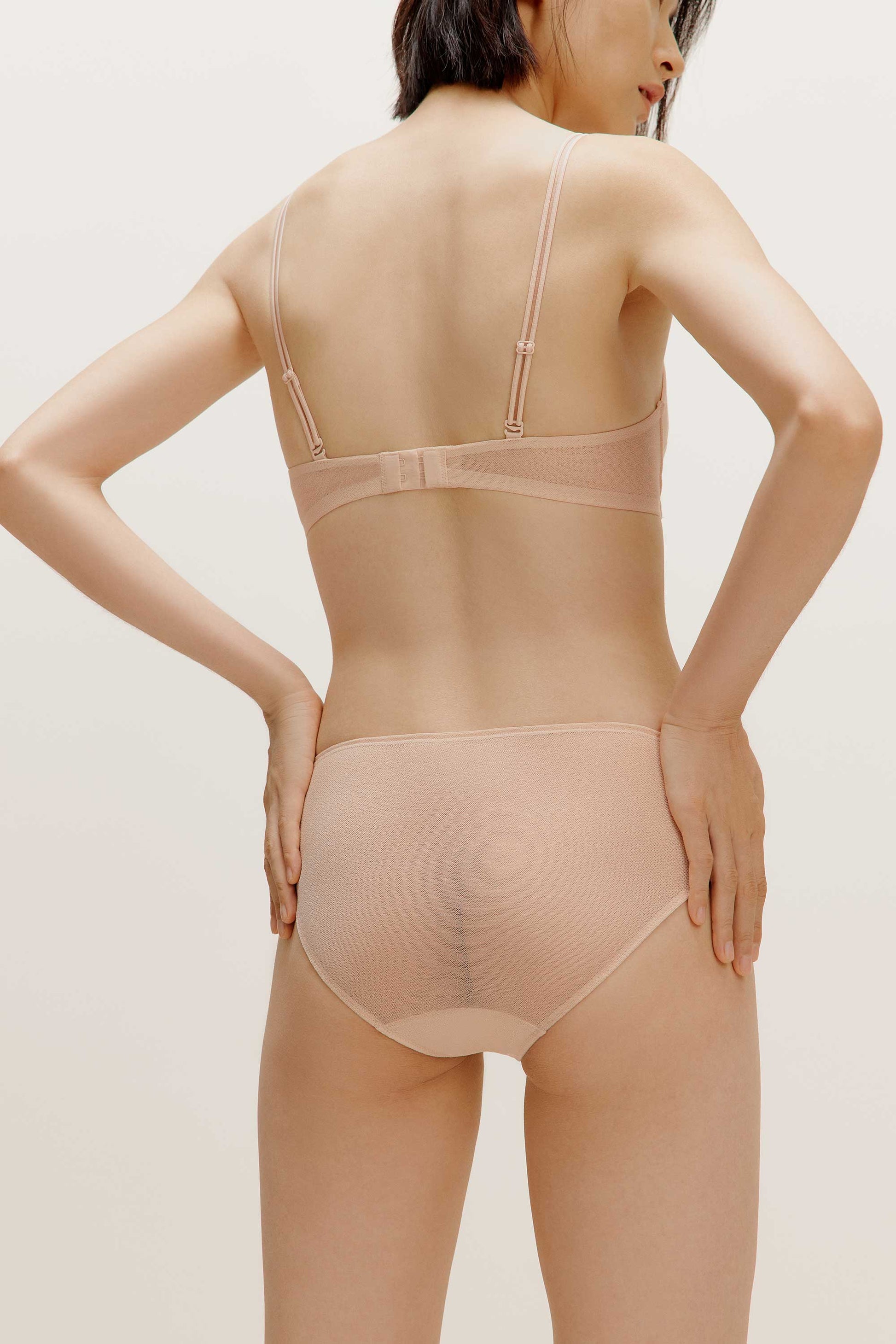 A woman wearing a nude bra and brief from back