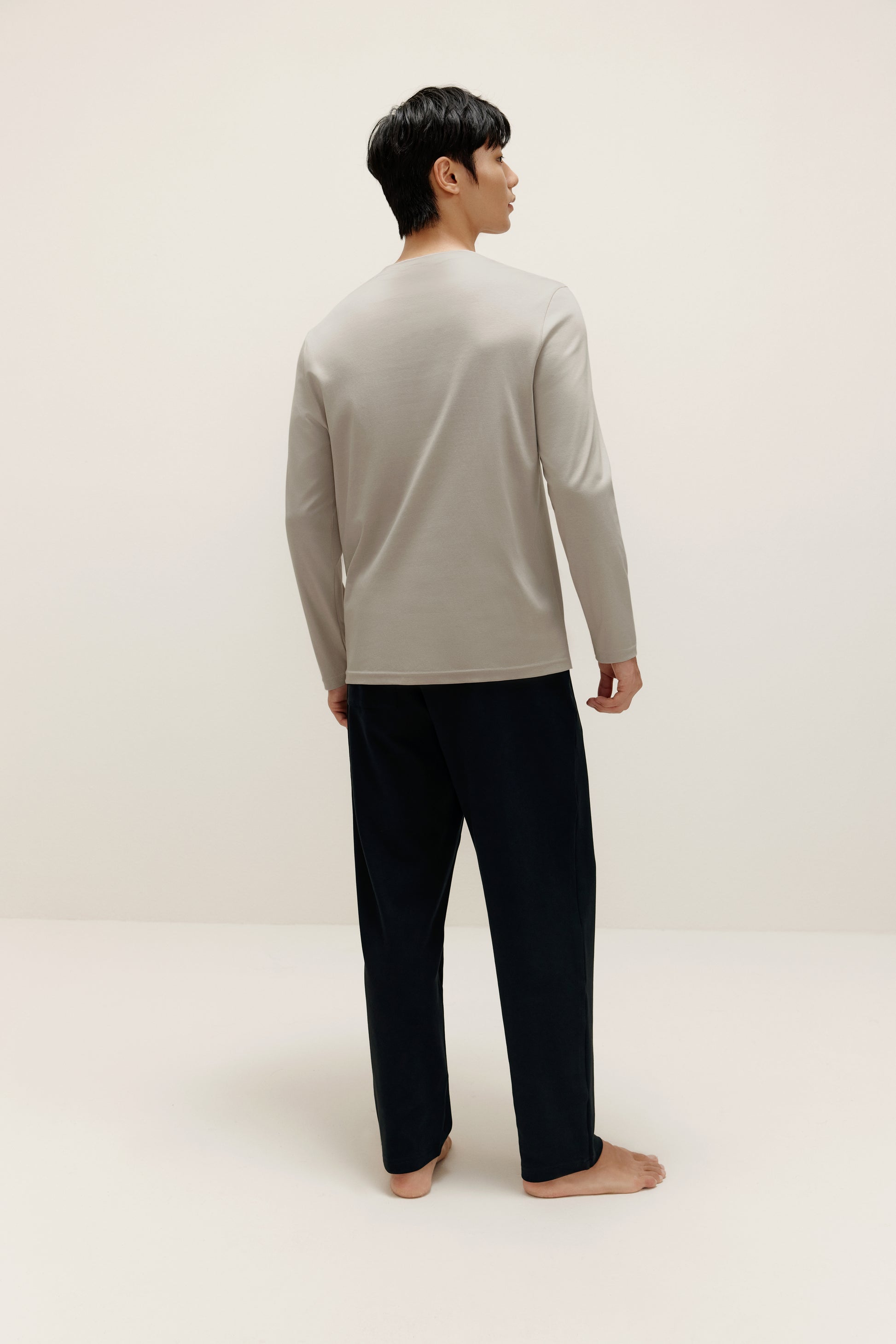 back of man wearing a grey long sleeve and black pants