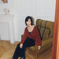 woman sitting on the sofa wearing a red wrap Cardigan and black pants