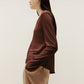 side view of the brown sweater and beige pants.