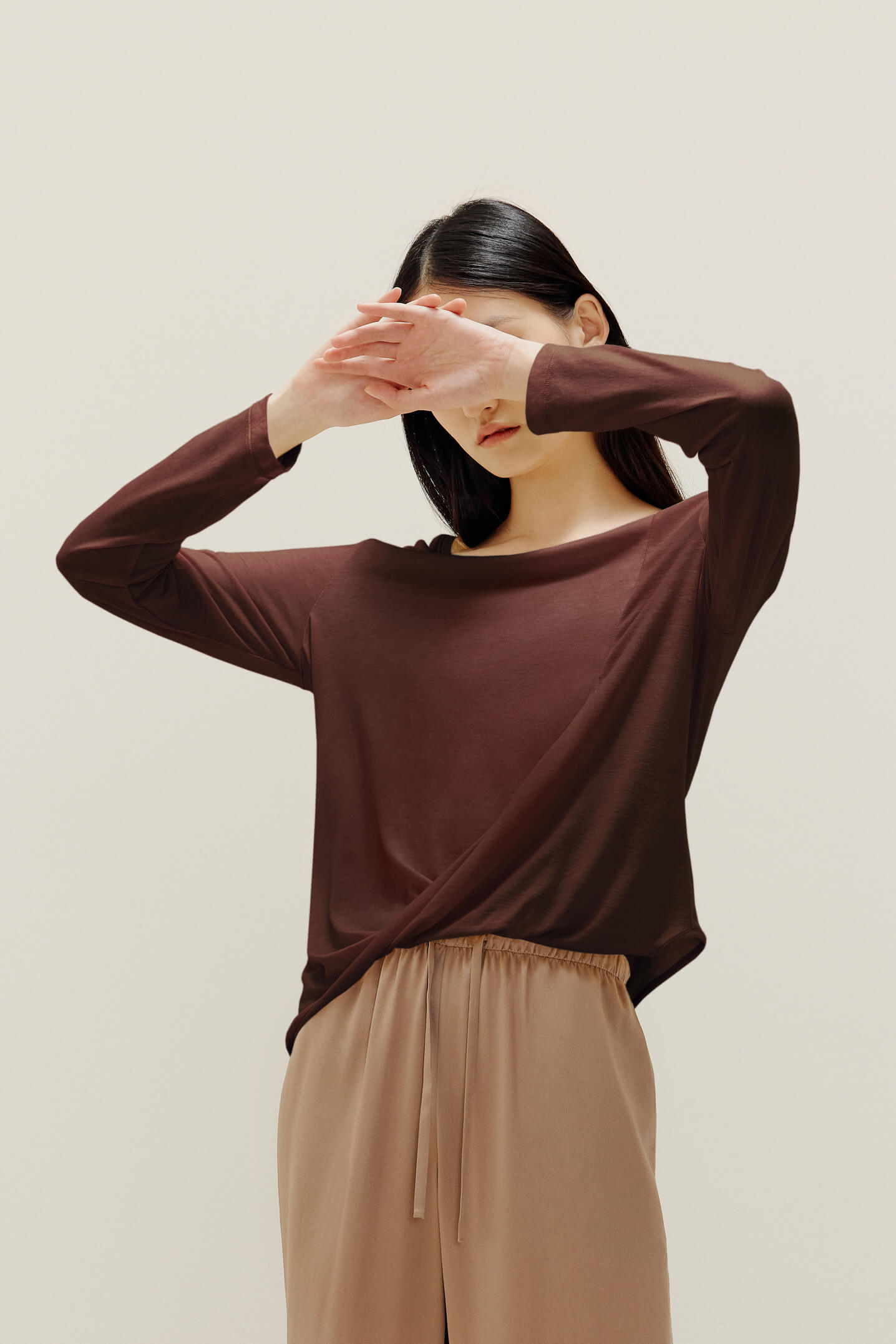 A woman wears a brown sweater and beige  pants