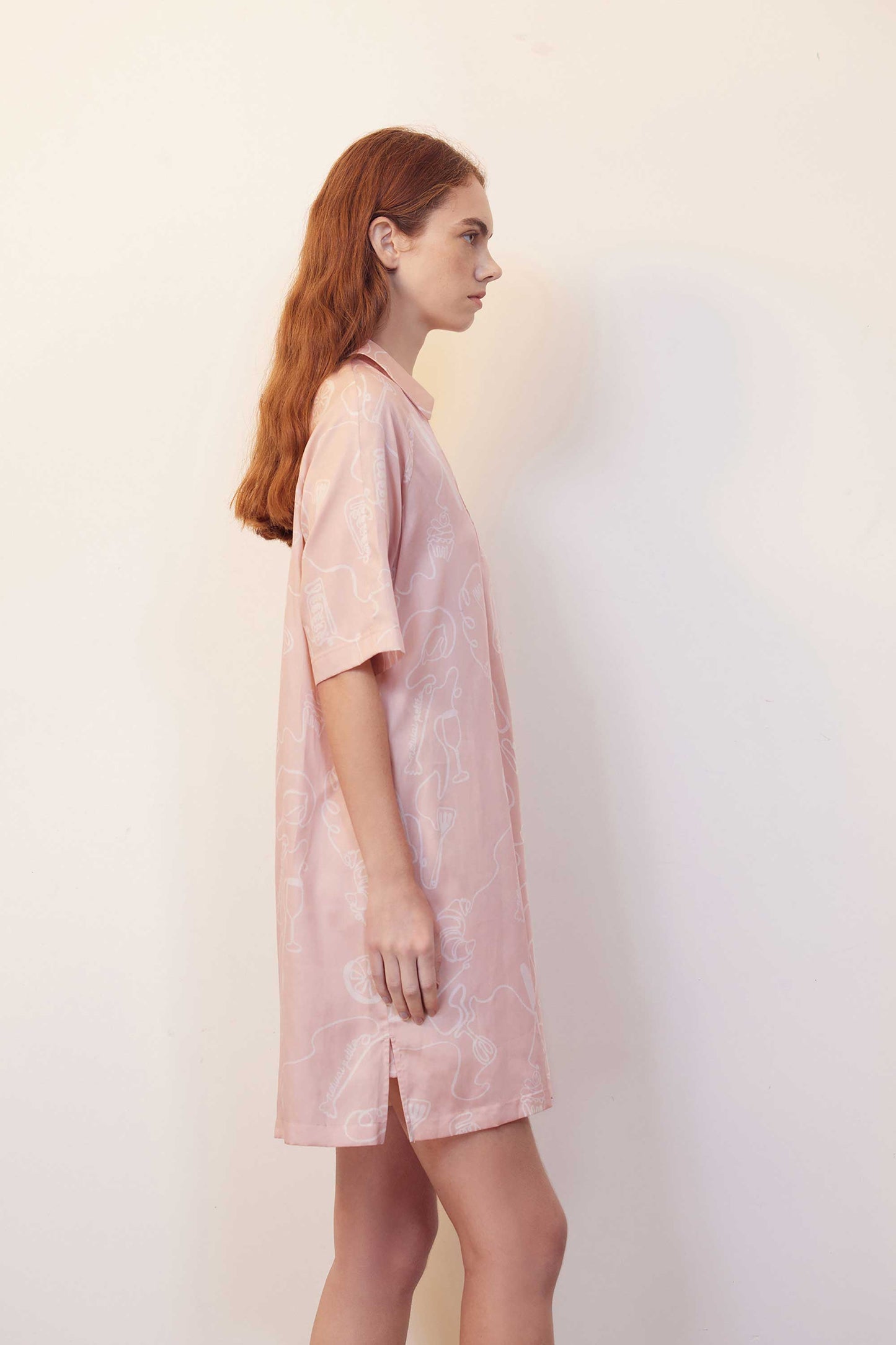 side of woman with pink pajama dress with white sketches