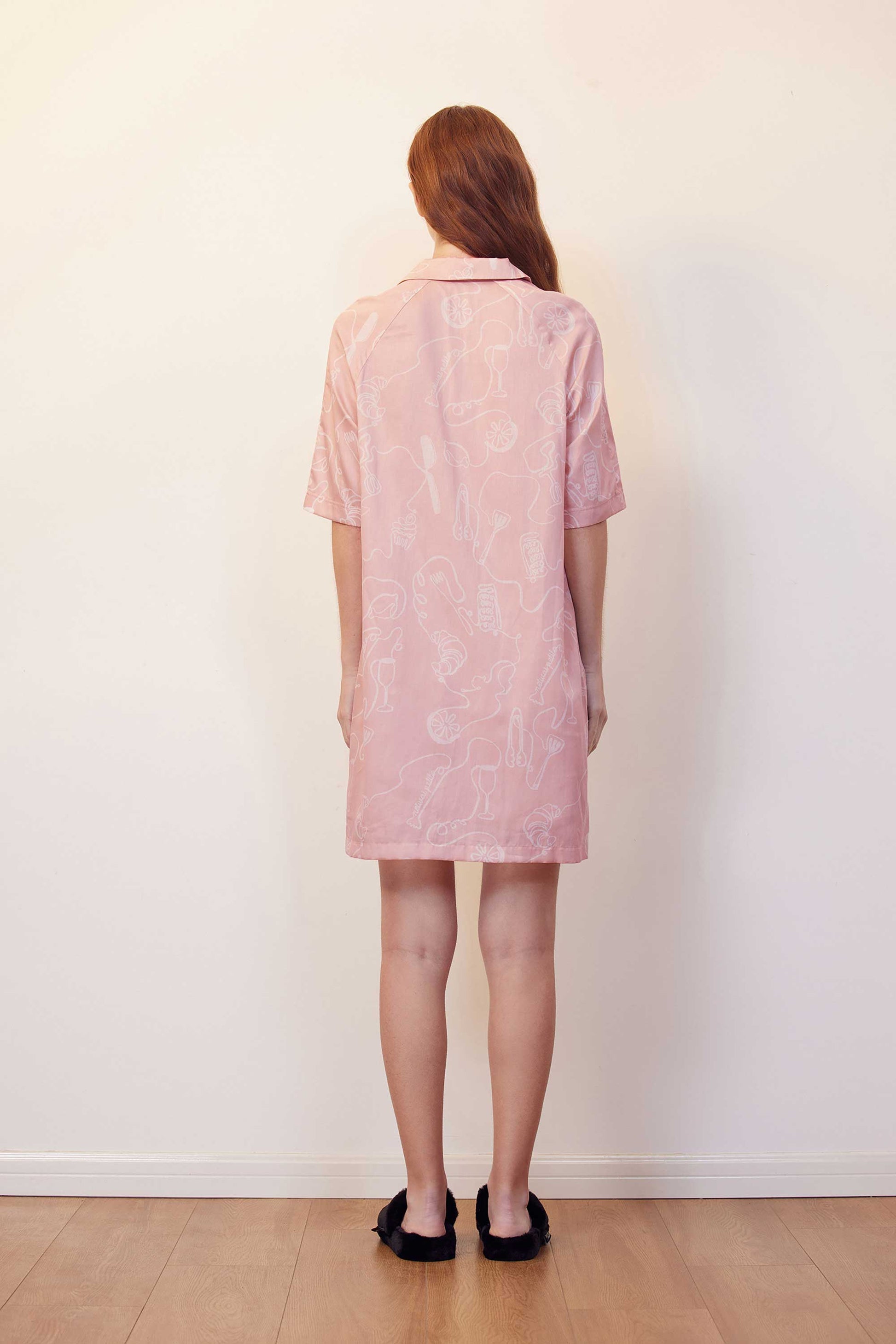 back of woman with pink pajama dress with white sketches
