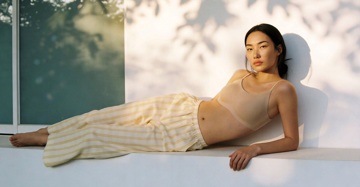A woman wearing a nude color strap bra lying outdoor