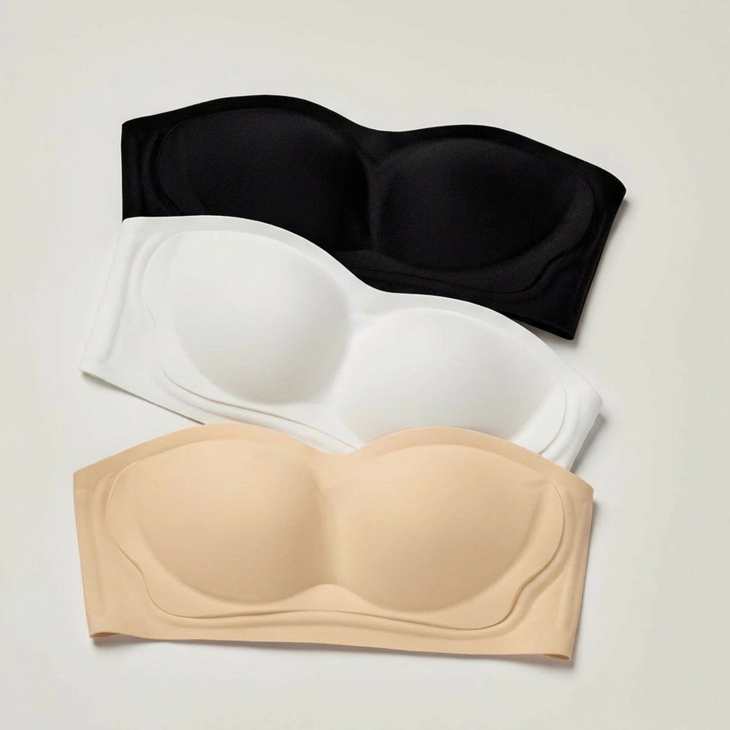 Black, white, and beige strapless bras on a light gray background
