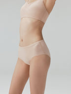 Side view of model wearing nude mid-waist briefs