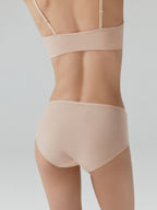 Back side of model wearing nude bra and mid-waist briefs