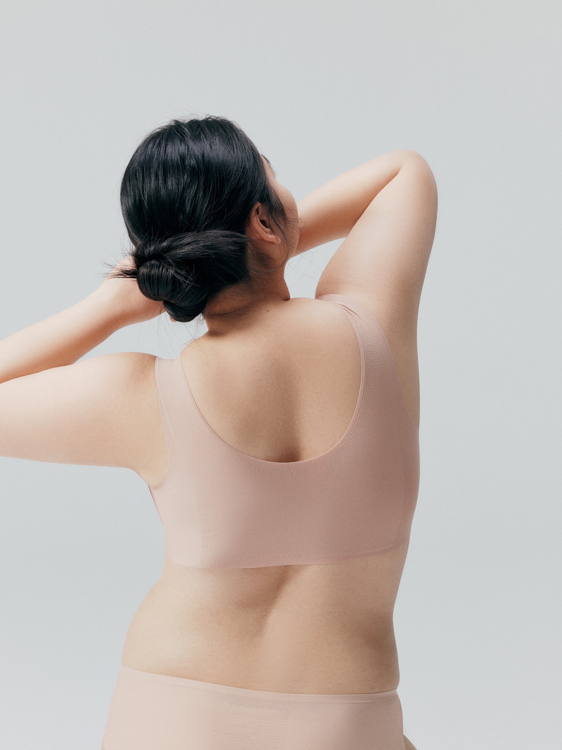 Back side of model wearing a nude bra and brief set.