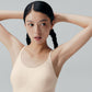 Model wearing Barely Zero cream colored bra with arms raised.