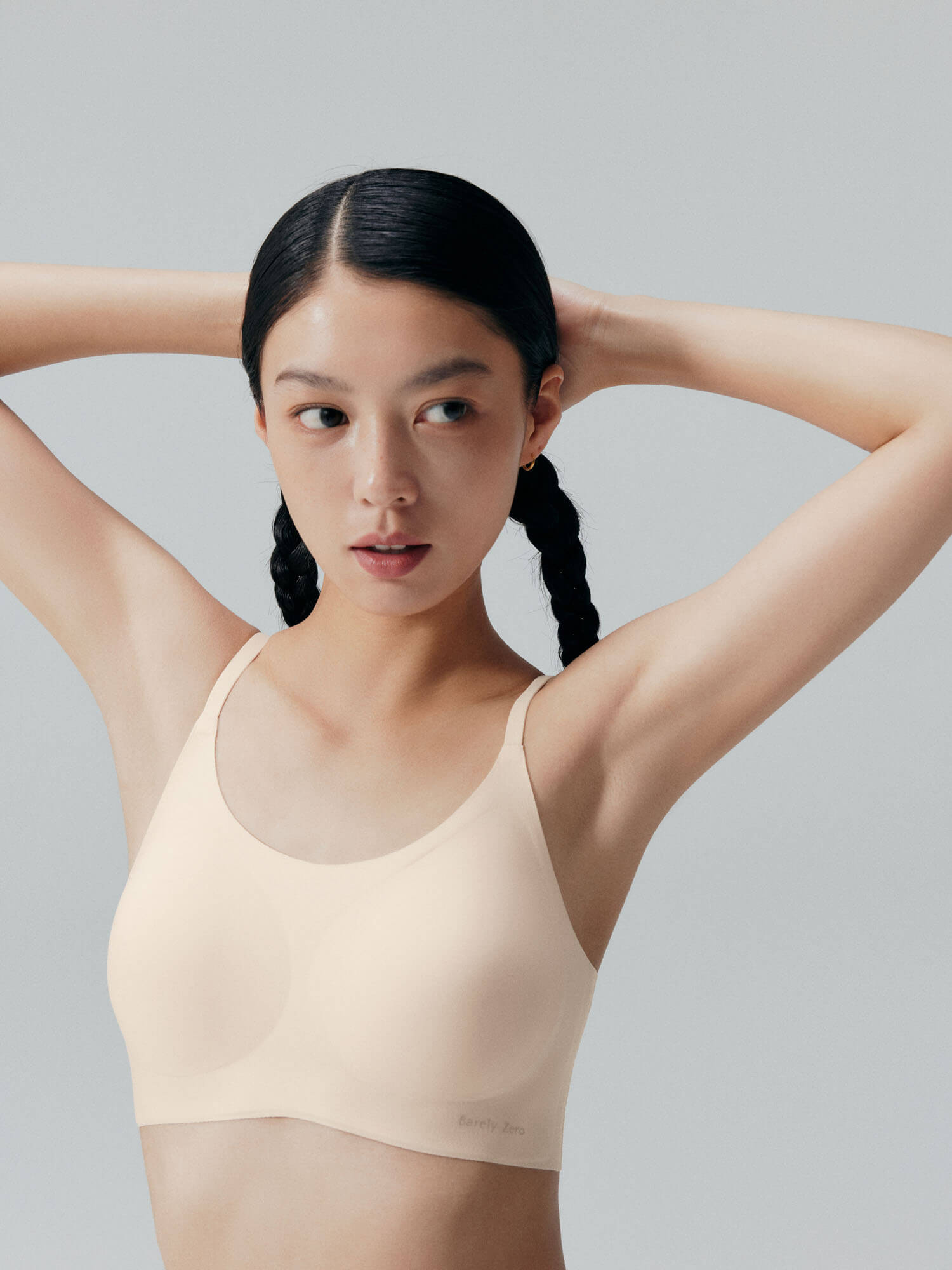 Model wearing Barely Zero cream colored bra with arms raised.