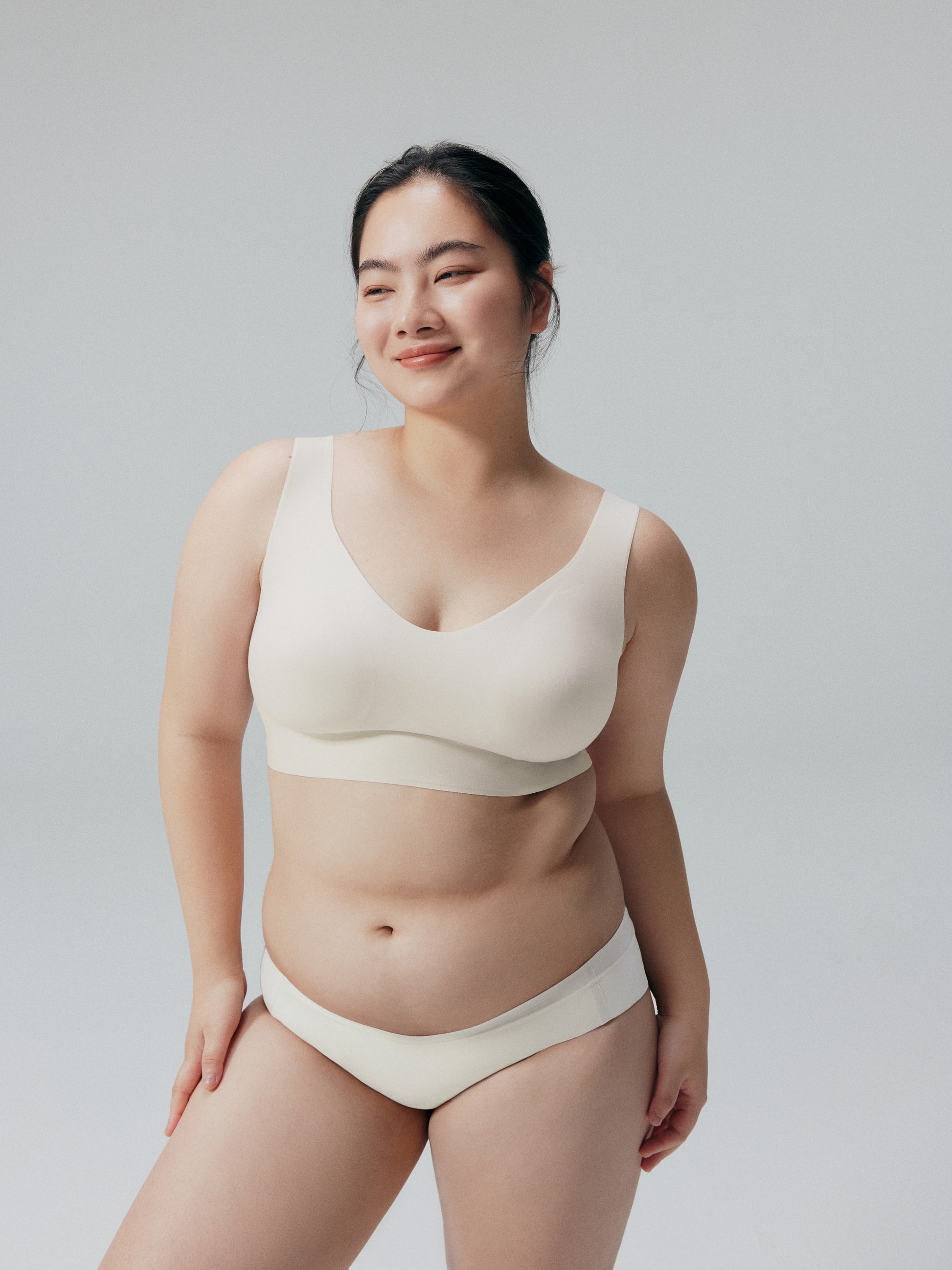 Model wearing a beige bra and brief set against a plain background.