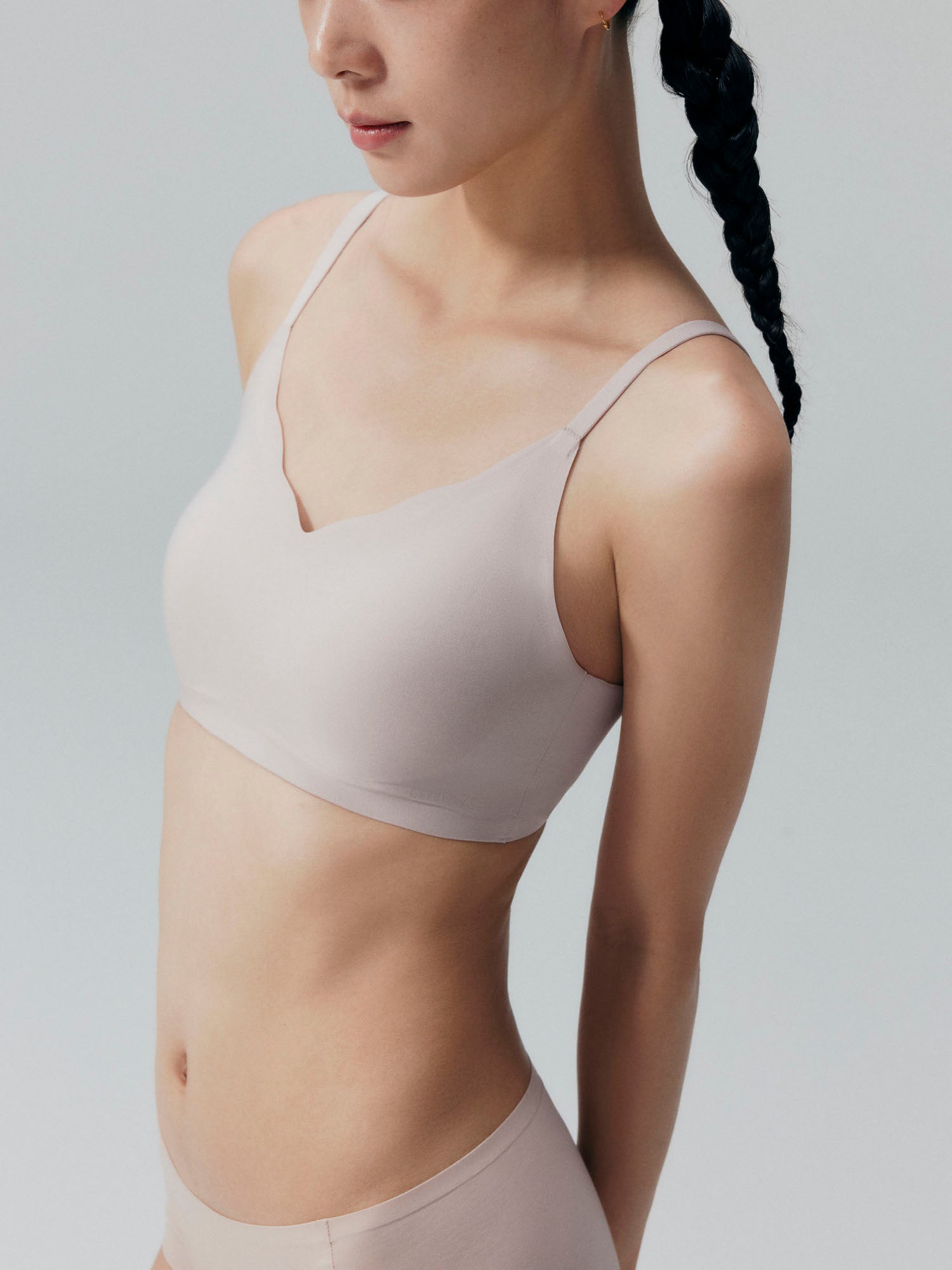 Side view of model wearing nude colored bra and brief set.