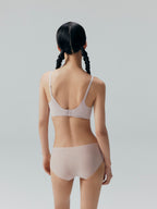 Back side of model wearing nude colored bra and brief set.