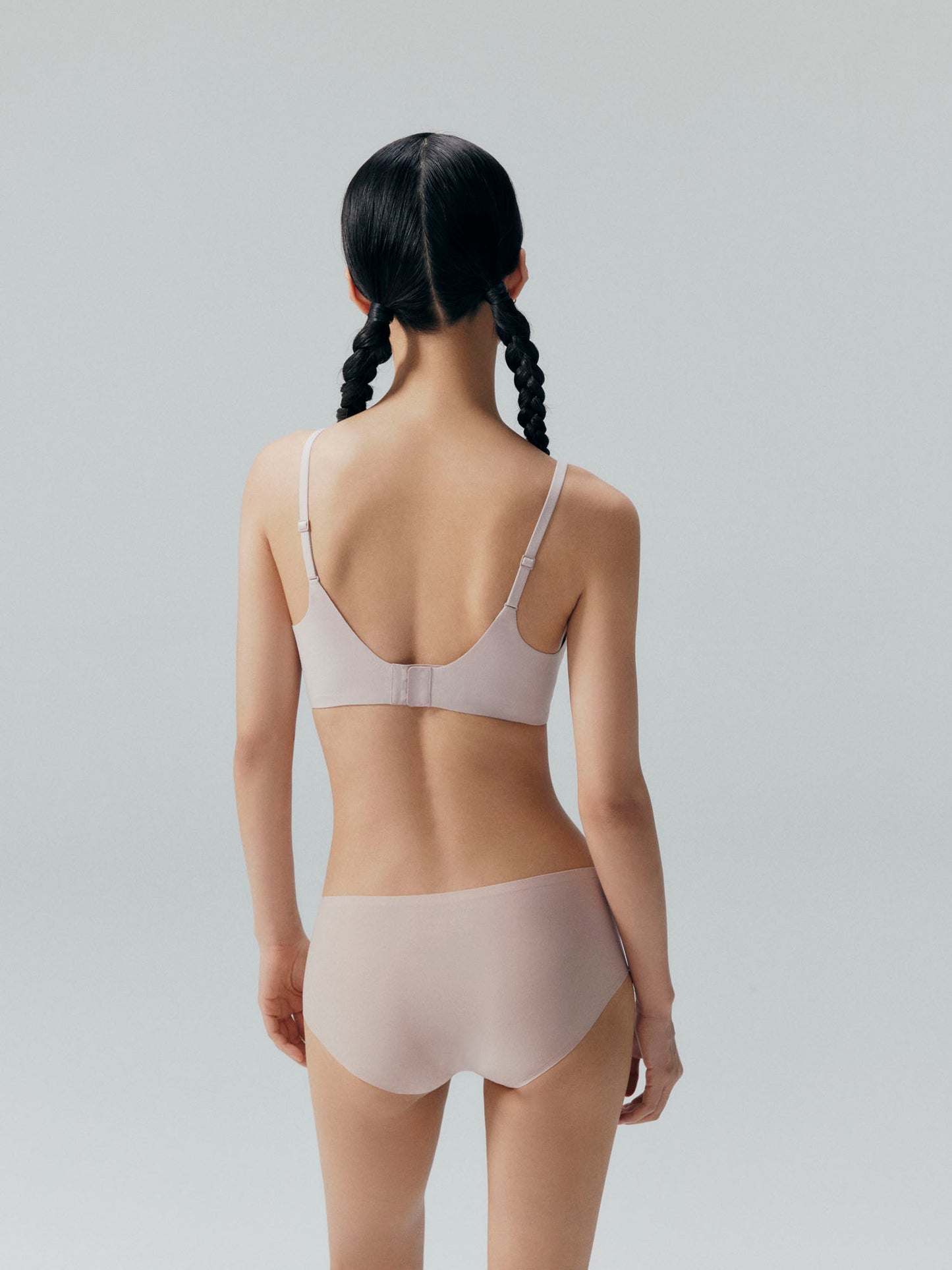 Back side of model wearing nude colored bra and brief set.