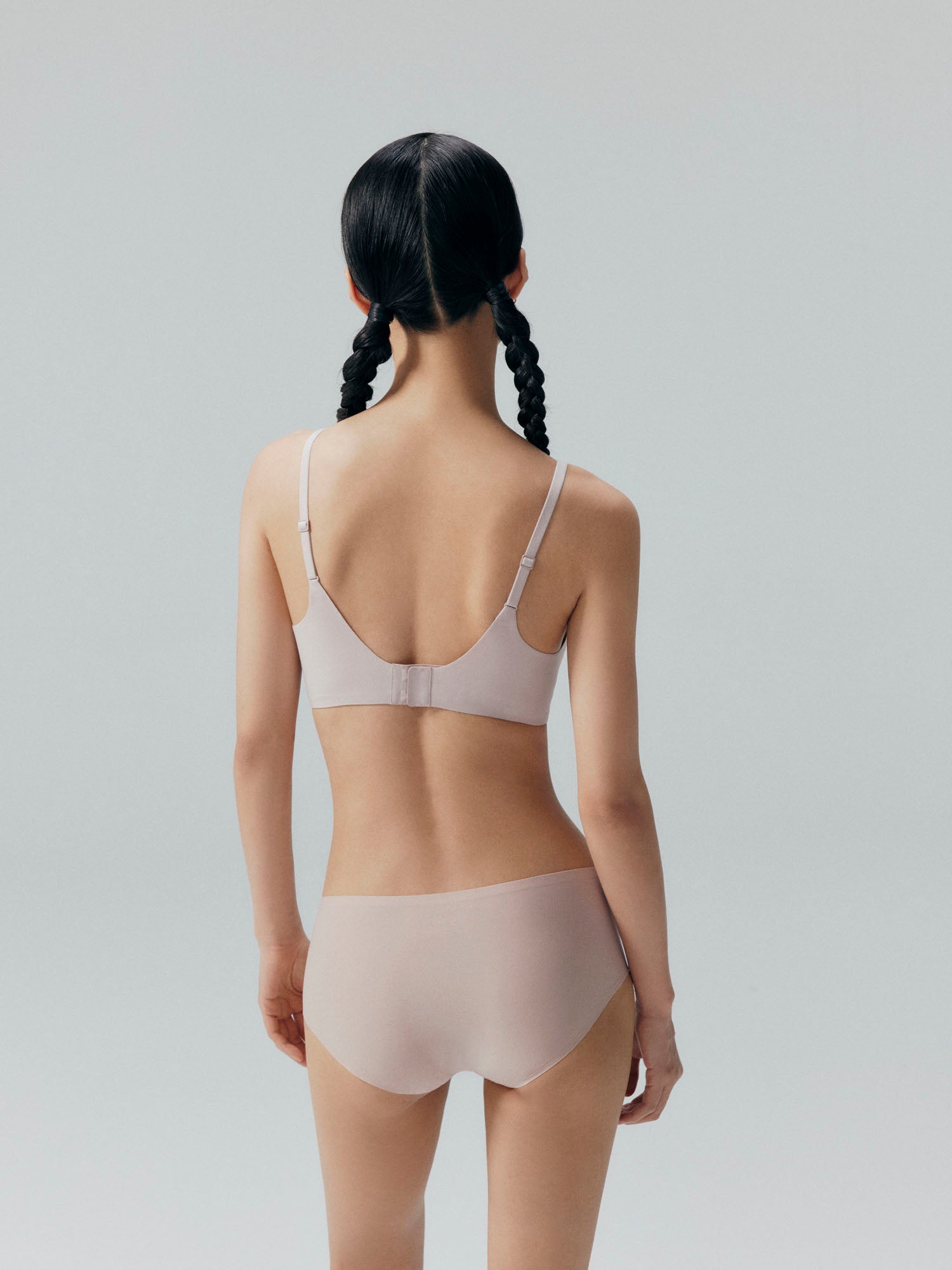 Back side of model wearing nude colored bra and brief set.