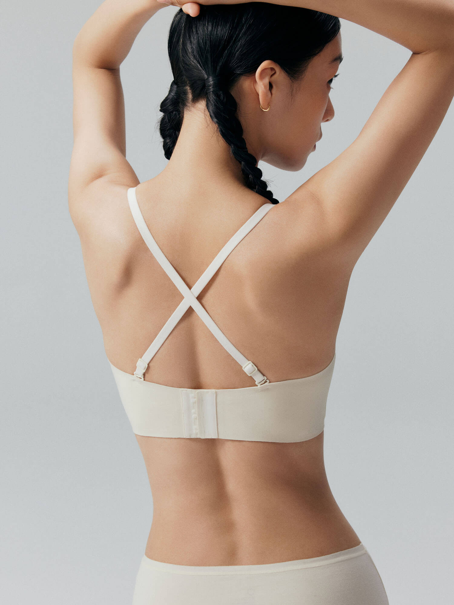 Back side of model wearing white bandeau bra and briefs with back cross straps. Eggwhite color.
