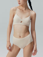 Model wearing a beige bra and brief set on a plain background