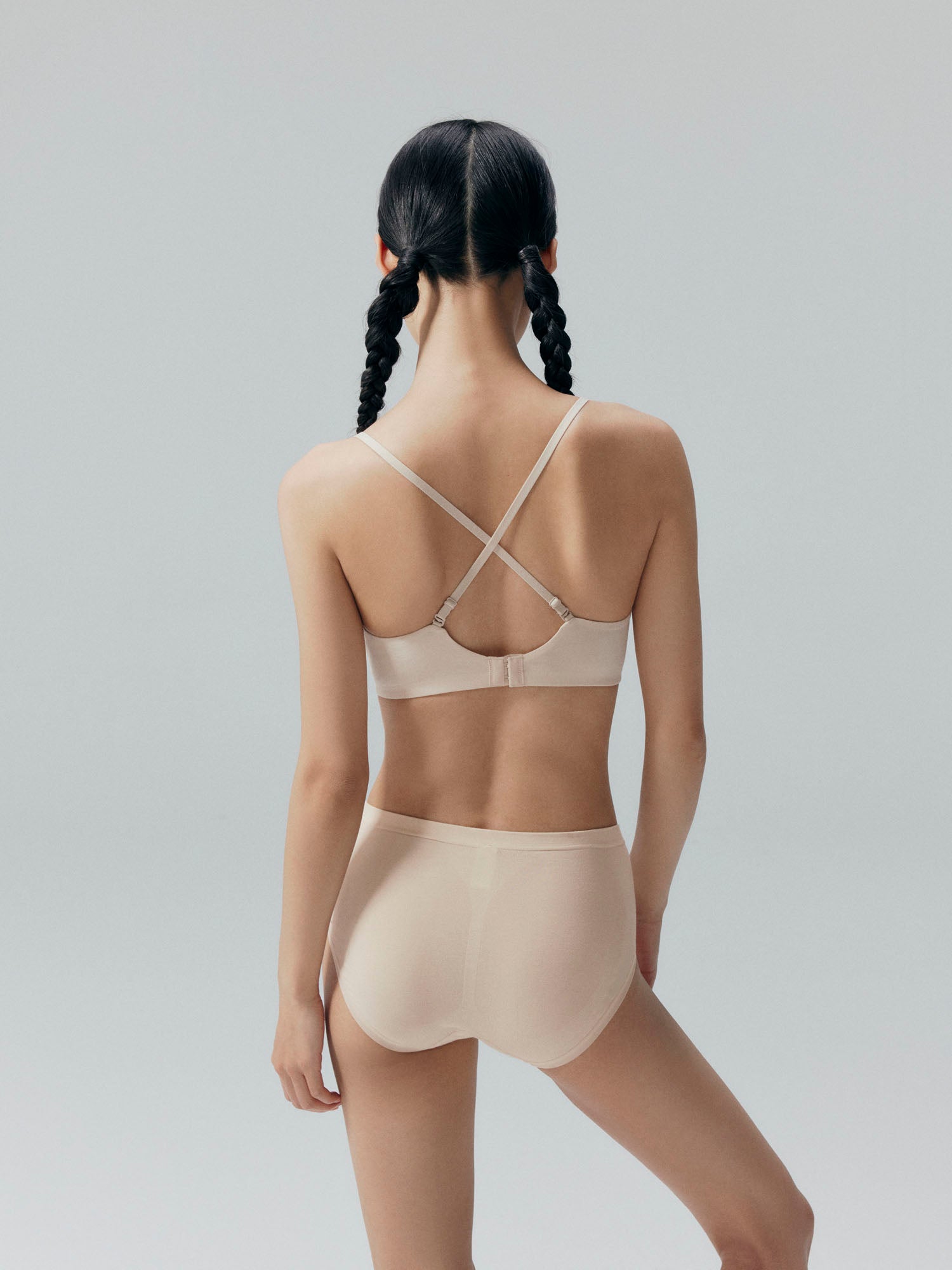Back view of model wearing a beige bra with racerback straps and matching briefs.