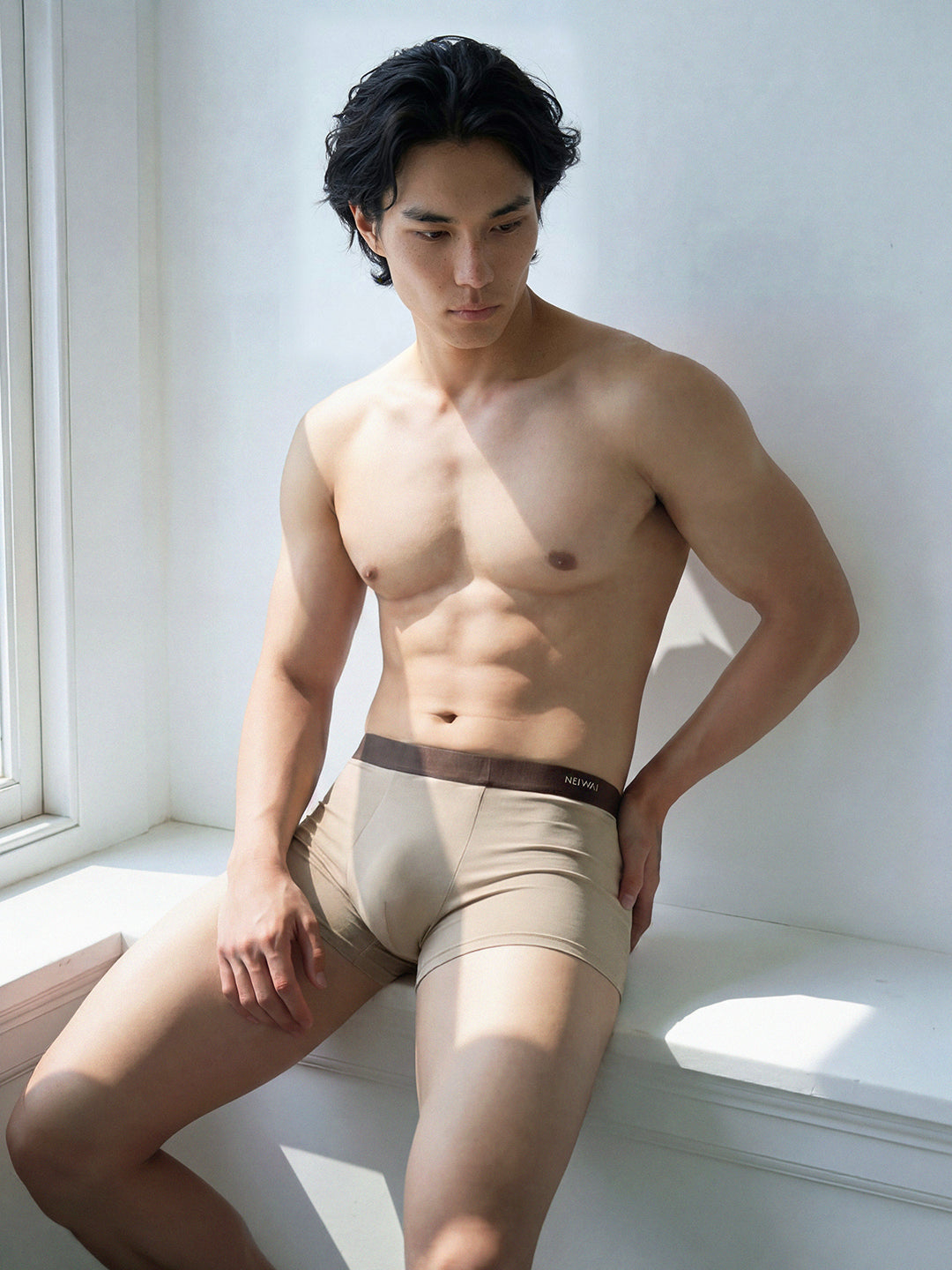 Male model in briefs standing by window. Light Heather color. 