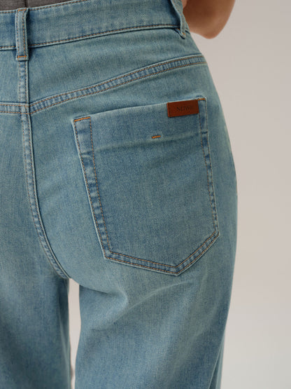 Close-up of blue jeans with a brand label on the pocket against a neutral background