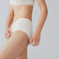 Side view of model wearing cream colored bra and brief set