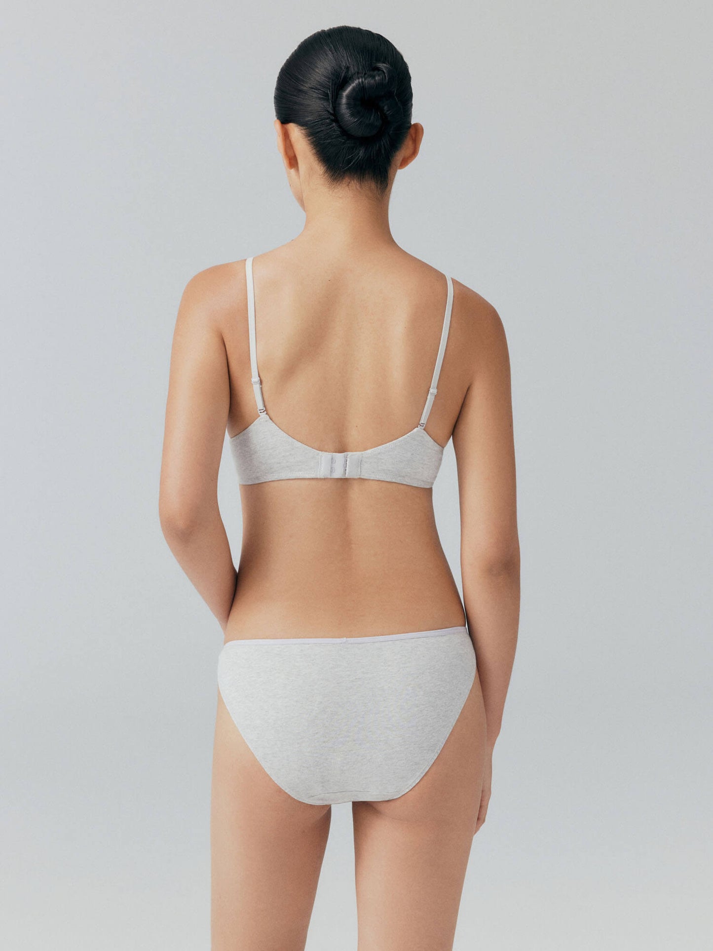 Back view of model wearing light gray bra and brief set.