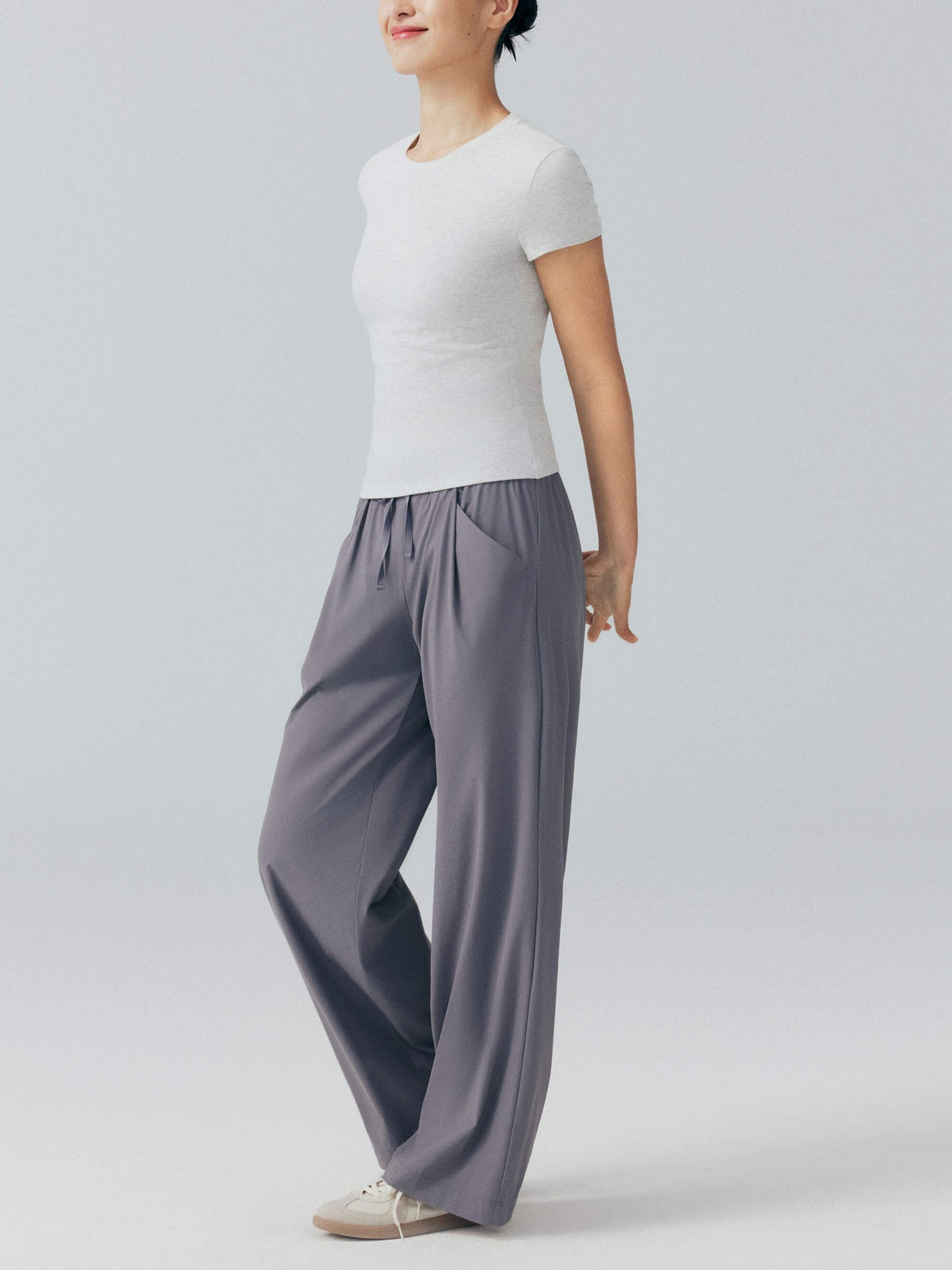 Side view of woman wearing white tee with gray pants.