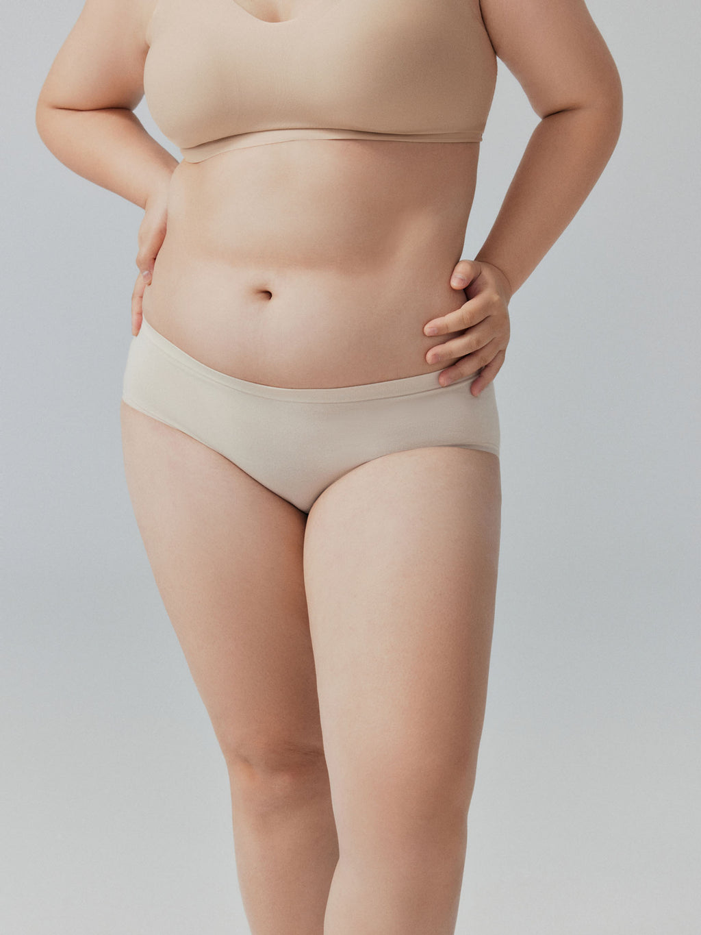 Model wearing beige underwear on a plain background.