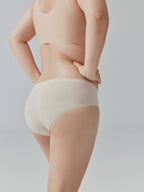 Model wearing beige tank top and underwear on a plain background.