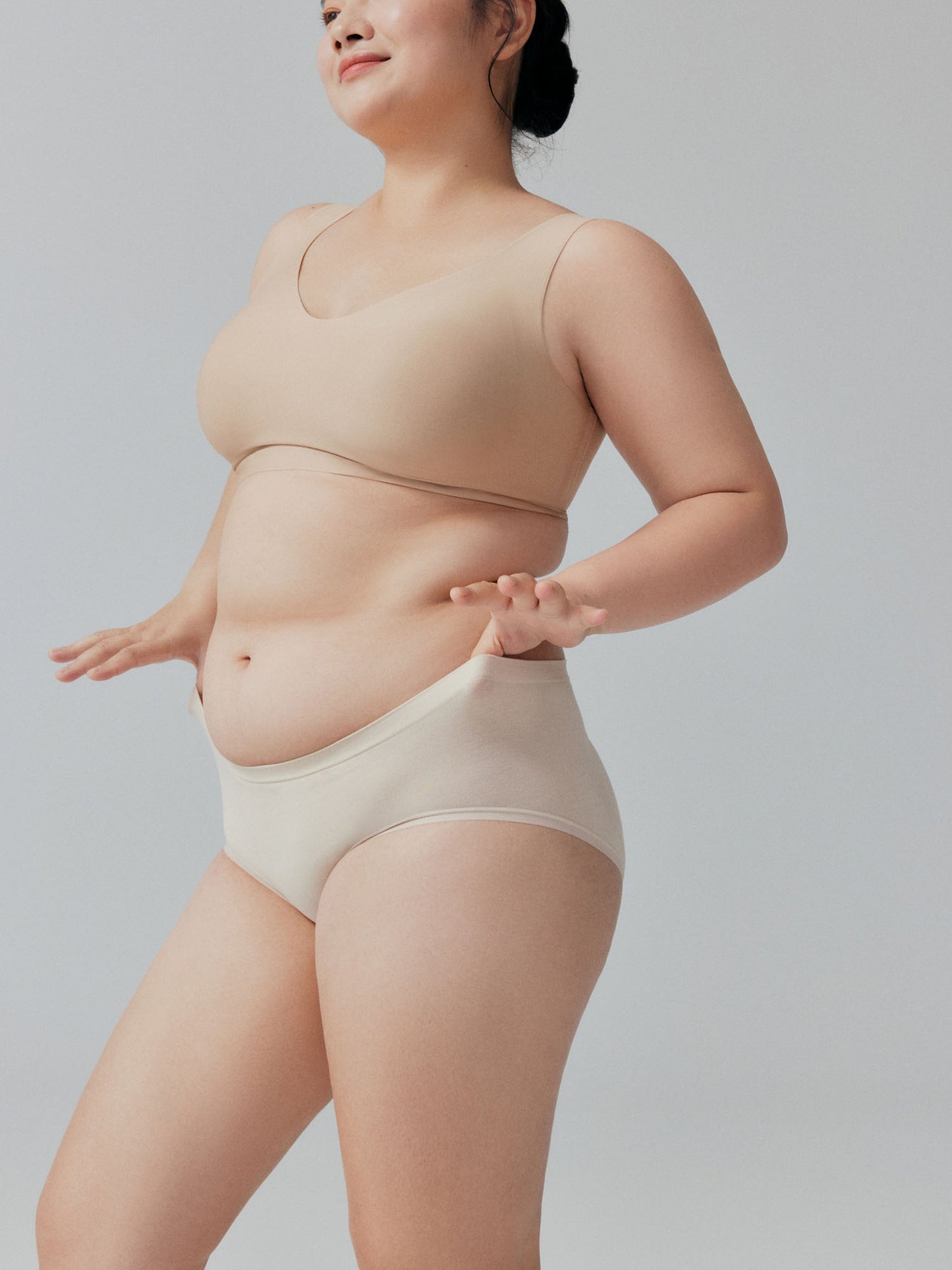 Model wearing beige bra and briefs on a plain background.
